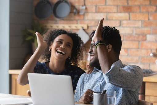 Two people looking at a computer and smiling