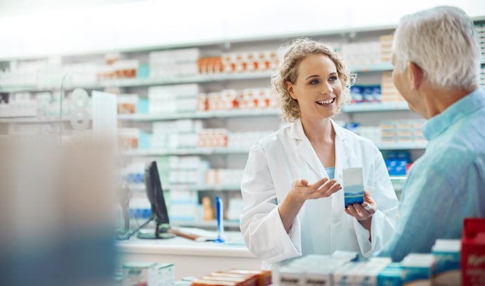 A pharmacist serves a customer.