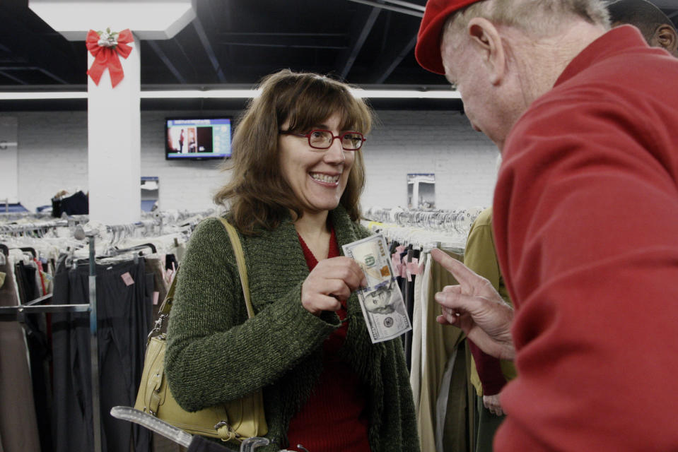 Valerie Daval reacts to receiving a $100 bill from Secret Santa, right, a man from Kansas City who prefers to remain anonymous, at a Salvation Army thrift store in Los Angeles&#x002019; Lincoln Heights neighborhood on Friday, Dec. 13, 2013. He is a wealthy businessman who goes around anonymously at Christmas time, handing $100 bills to people he spies in places such as thrift stores, laundromats, health clinics, assistance centers and shelters. He gives away tens of thousands of dollars each year with no tax benefits. (AP Photo/Nick Ut)