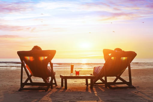mature couple relaxing on beach at sunset