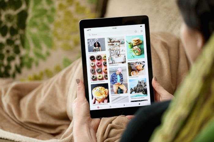 A person using a tablet to peruse pinned boards on social media site Pinterest.