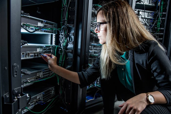 An engineer checking the wires and switches of data center server towers. 