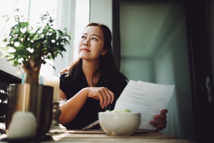 Person holding document, looking away. 