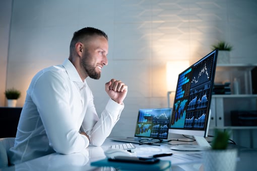 excited investor looks at financial charts on computer.