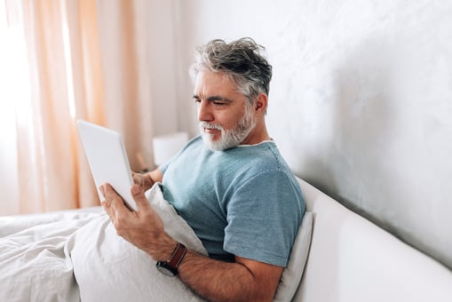 Older man tablet in bed GettyImages-1472399503