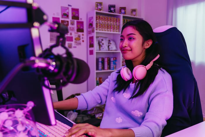 A person wearing headphones looks at a desktop.