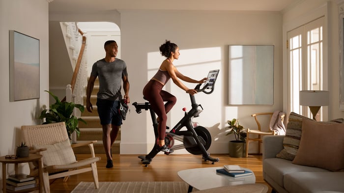 A couple sharing a Peloton bike in their home.