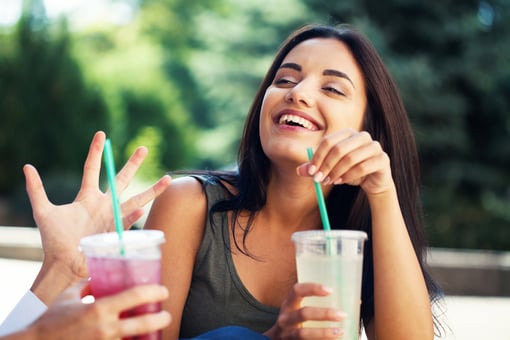 Young woman laughing and drinking soda