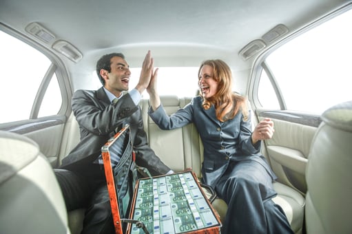 Man woman celebrating with cash in a car