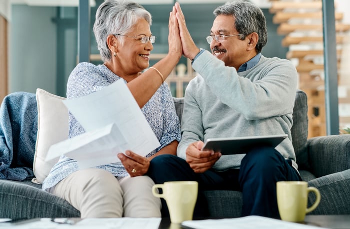 Two smiling people giving  each other a high five.