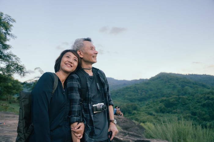 Two people outside hugging while looking out at nature.