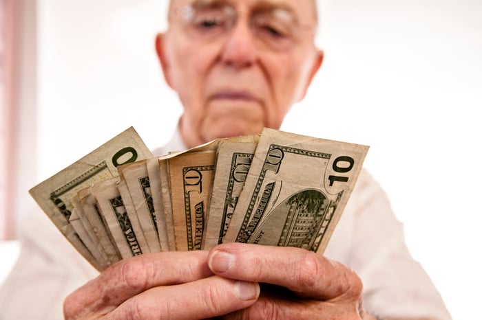 A person counting an assortment of fanned cash bills in their hands.