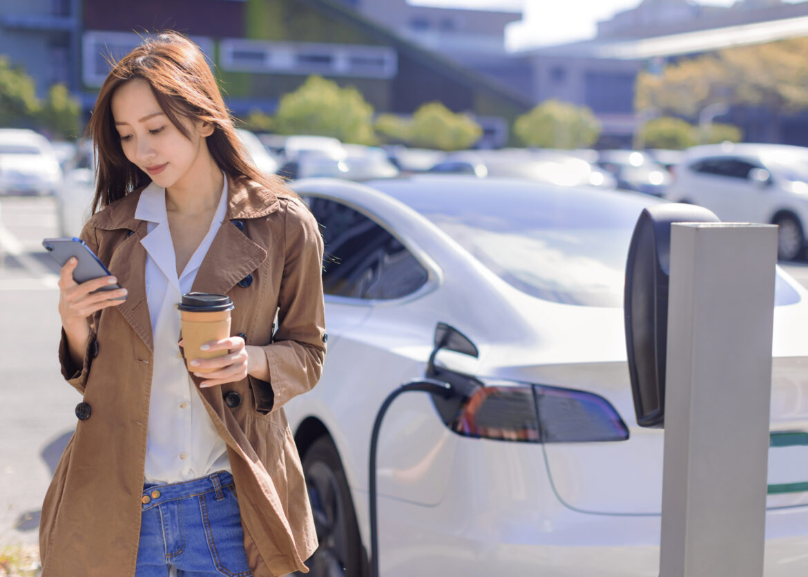 person-on-phone-stands-in-front-of-car-at-charging-station-getty.jpg