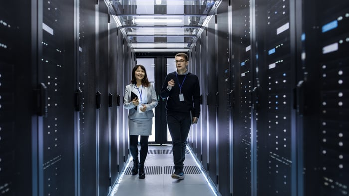 Two IT professionals walk through a server room.