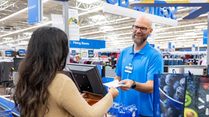 A Walmart associate speaking with a customer at the checkout stand.