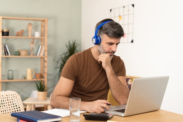 A person at a laptop wearing headphones.