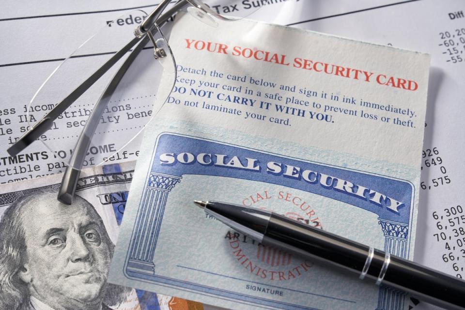 A Social Security card on a piece of paper with pen, glasses, and $100 bill.