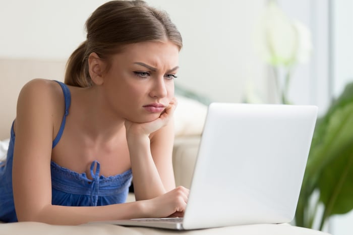 A person frowns while working on a computer. 