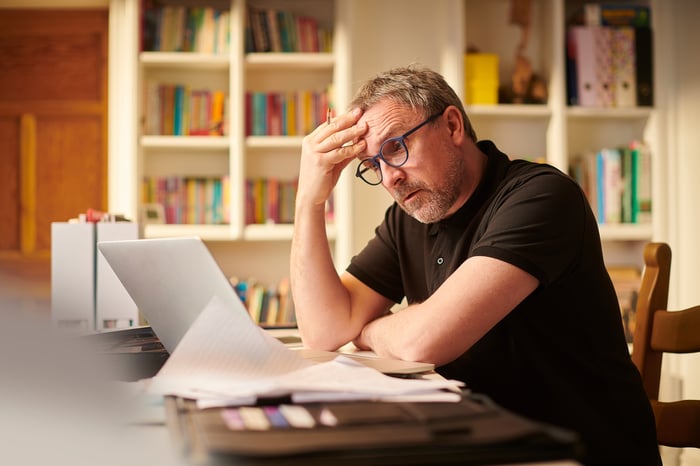 Overwhelmed person looking at laptop.