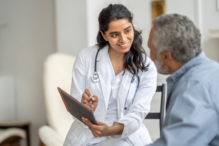 A person in a white coat talking to a patient.