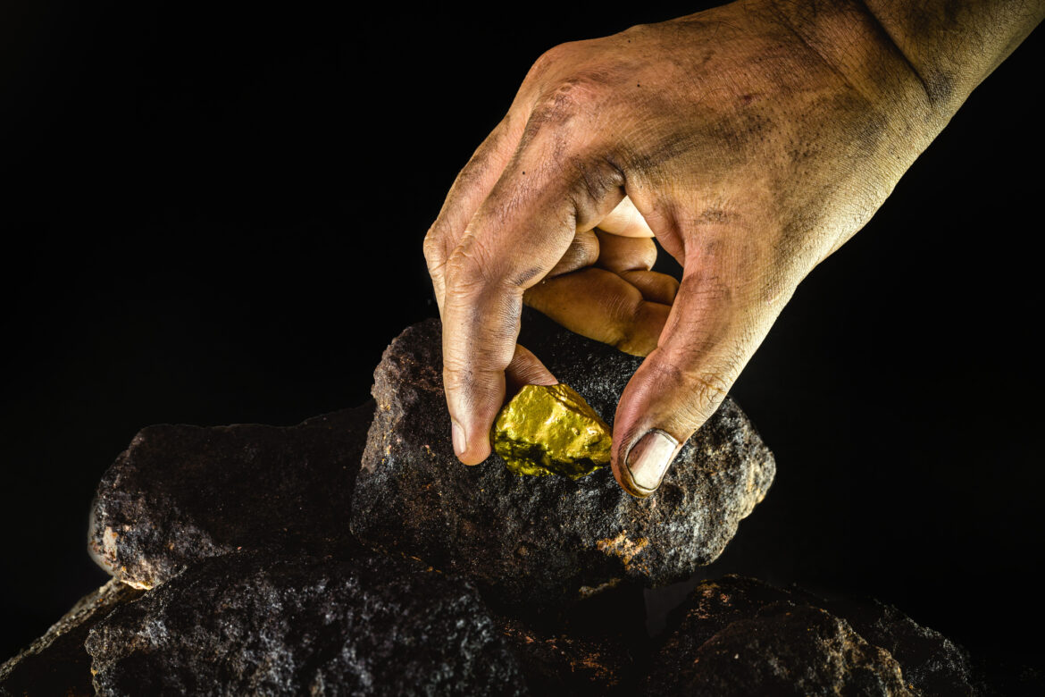 miner-picks-up-gold-nugget-from-dirty-ore.jpg
