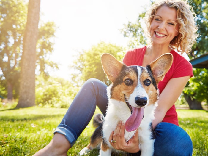 A happy person plays with a dog outside.