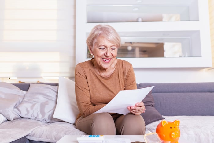 Person sitting on couch looking at a piece of paper.