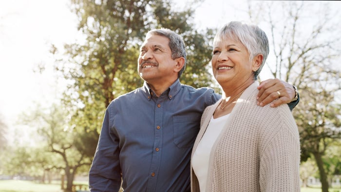 Two people standing outside and smiling.