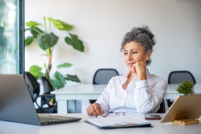 Person sitting at a desk and looking at an open laptop.