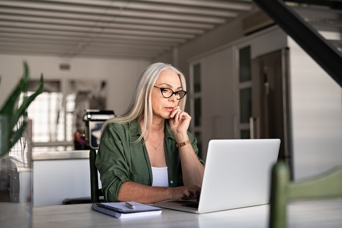 Someone sitting at a table using a laptop.