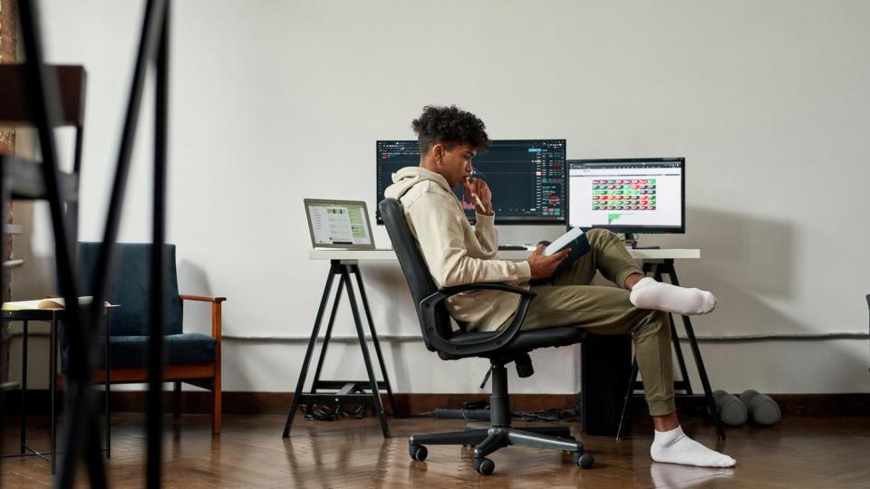Person looking at book in front of computer.