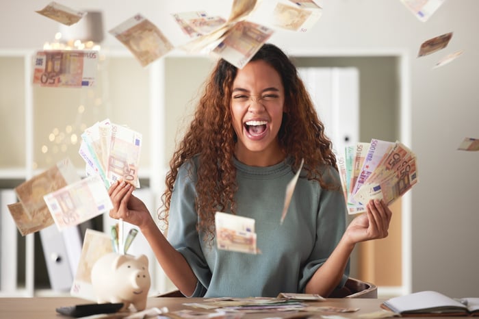 Happy young woman with bills raining down. 