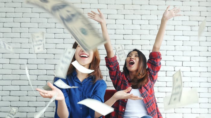 Two people laughing as money falls down on them from above.